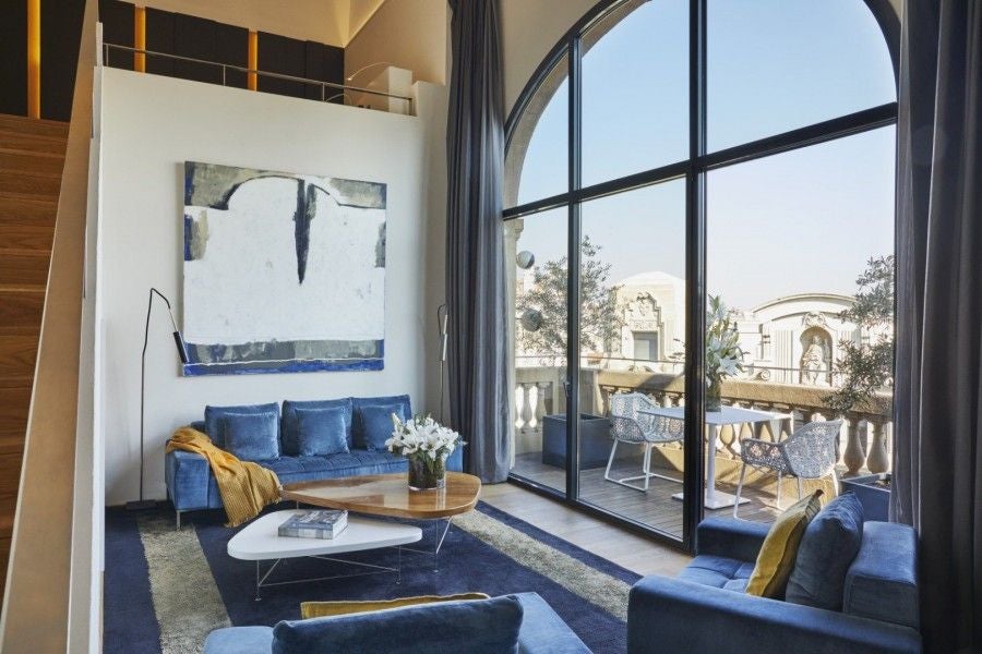 Contemporary luxury suite with floor-to-ceiling windows, minimalist design, panoramic city views, and elegant dome-shaped ceiling in Barcelona hotel room.