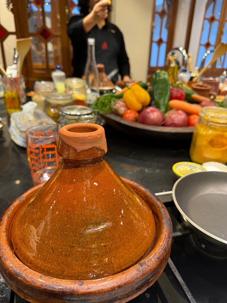 Vibrant cooking class in a luxurious Moroccan kitchen, participants wearing crisp white aprons, surrounded by colorful spices and traditional cookware