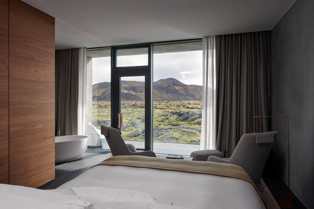 Minimalist Icelandic luxury suite with panoramic scenset lagoon view, sleek modern design, floor-to-ceiling windows, and soft neutral color palette