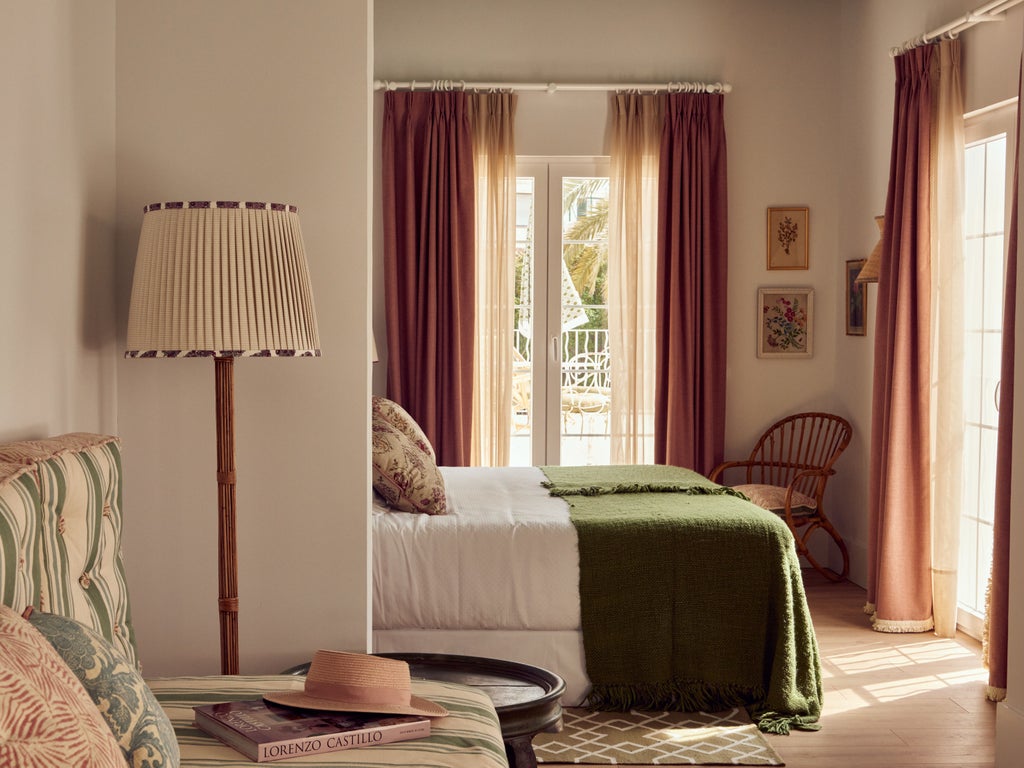 Elegant Spanish boutique hotel with whitewashed facade, wrought-iron balconies, and lush greenery framing arched windows and doorways