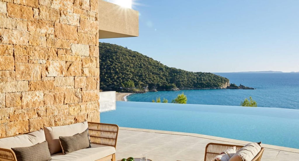 Luxurious coastal hotel with sleek white architecture, infinity pool overlooking azure Grecian waters, blending modern design with stunning Mediterranean landscape