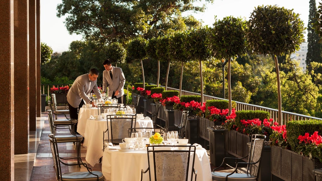 Elegant hotel facade with grand marble columns, ornate balconies and lush gardens, overlooking Lisbon's historic avenue at sunset