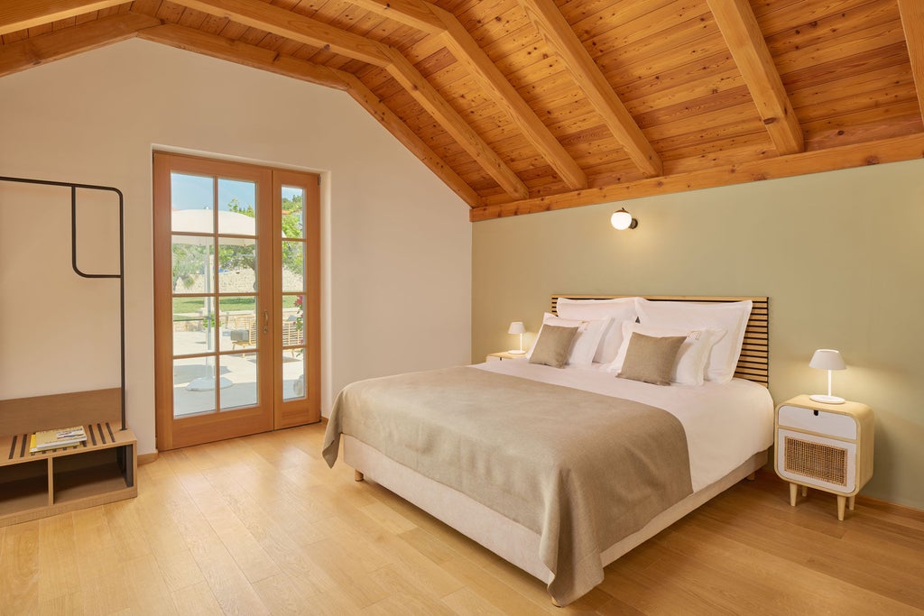 Spacious garden-view hotel room with king bed, elegant cream decor, floor-to-ceiling windows, and modern wood furnishings