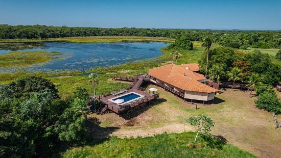 Luxurious private villa bedroom at Caiman Ecological Refuge, showcasing elegant decor with tropical Brazilian wilderness visible through large windows