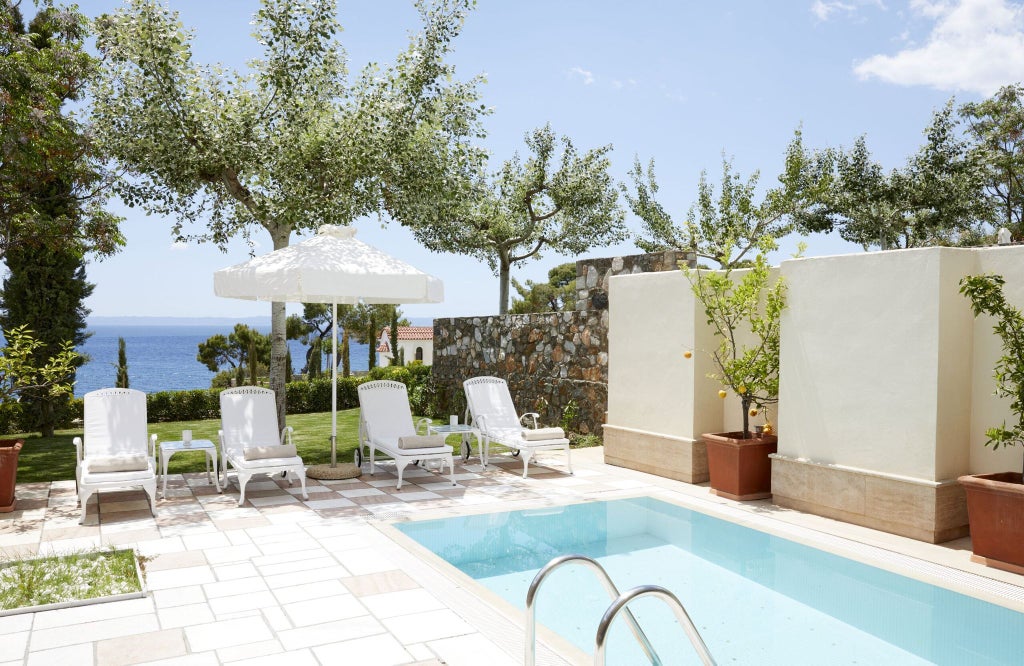 Luxurious two-bedroom pool suite at beach resort, featuring elegant white interiors, private pool, and stunning Aegean Sea view in Greece