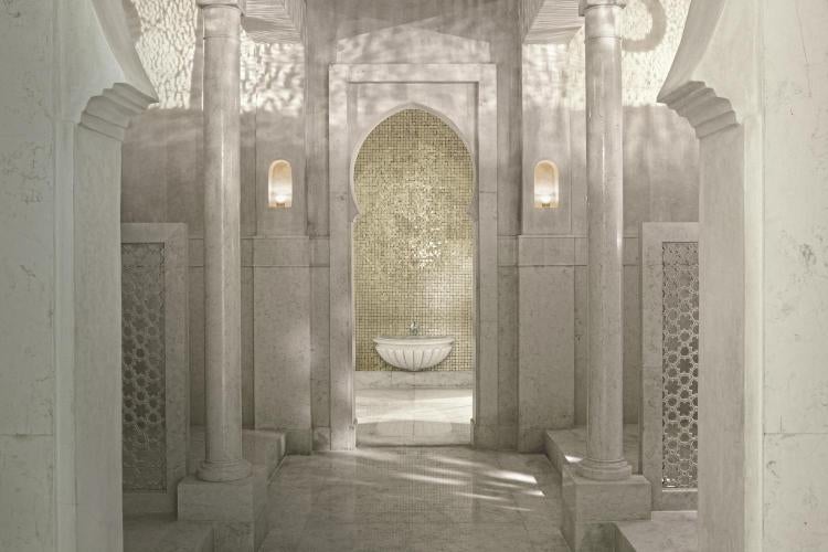 Opulent Moroccan hotel facade featuring white Art Deco architecture, grand entrance with brass details, and manicured palm trees