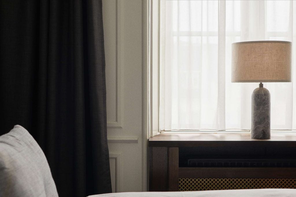 Elegant small deluxe hotel room in Denmark with luxurious minimalist design, crisp white linens, modern furnishings, and soft natural lighting