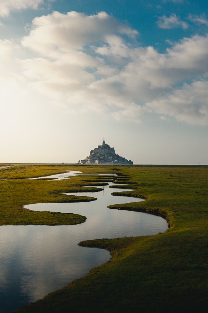 Scenic World War II memorial landscape with weathered stone monument, dramatic coastline, and tranquil beaches of Normandy under soft golden sunlight