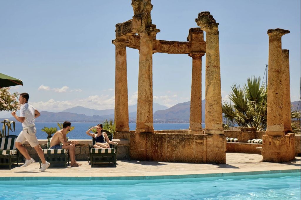 Historic Mediterranean luxury hotel Villa Igiea with grand stone facade, ornate balconies, and manicured gardens overlooking Palermo's coast