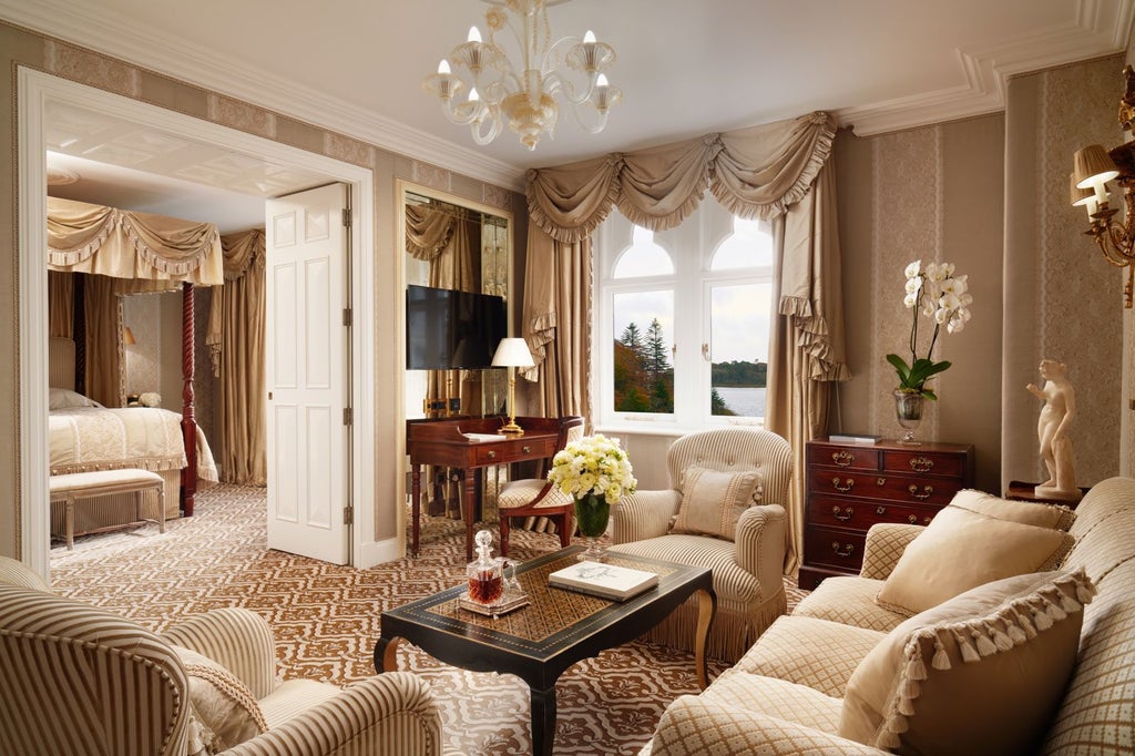 Opulent junior stateroom with antique furnishings, four-poster bed, ornate gold mirrors, and floor-to-ceiling windows overlooking castle grounds