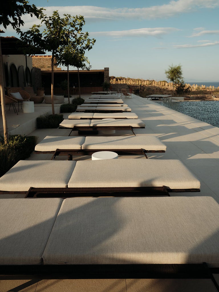 Elegant white-walled boutique hotel in Greece with private infinity pools overlooking the Mediterranean Sea at sunset