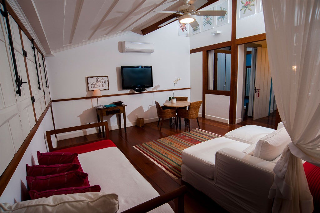 Luxurious red-themed hotel suite with elegant decor, featuring plush bedding, decorative artwork, and vibrant Brazilian design in Casa Turquesa, Paraty