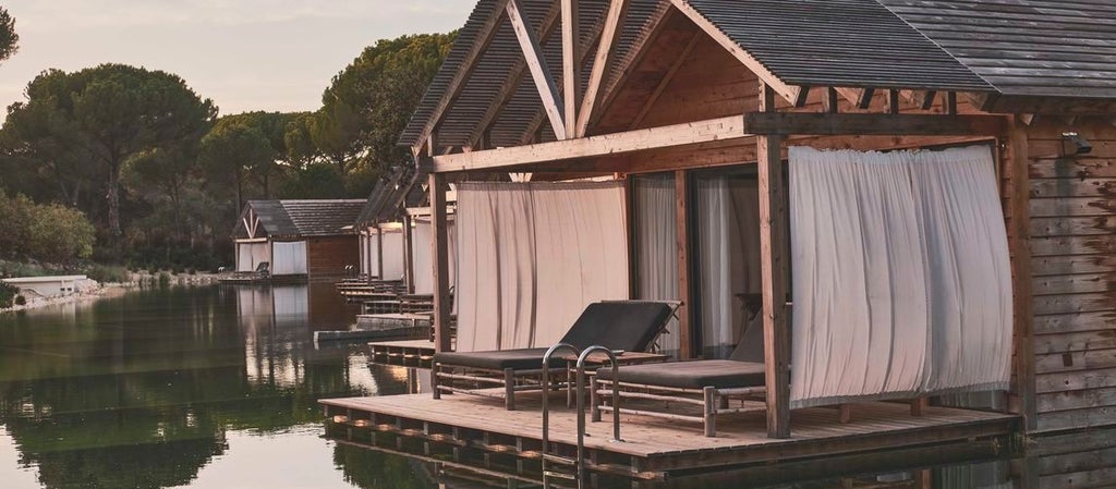 Minimalist luxury suite with natural wood accents, overlooking tranquil bio-pool at Sublime Comporta Hotel, soft earth tones blending seamlessly with Portuguese landscape