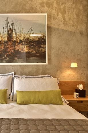 Elegant boutique hotel suite with warm neutral tones, plush king bed, vintage architectural details, and Maltese limestone walls in soft evening light