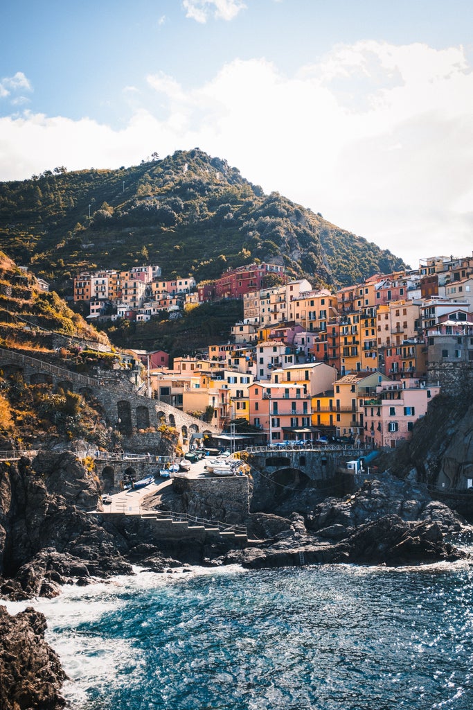 Colorful cliffside houses of Manarola village in Cinque Terre, Italy, overlooking turquoise Mediterranean waters at sunset