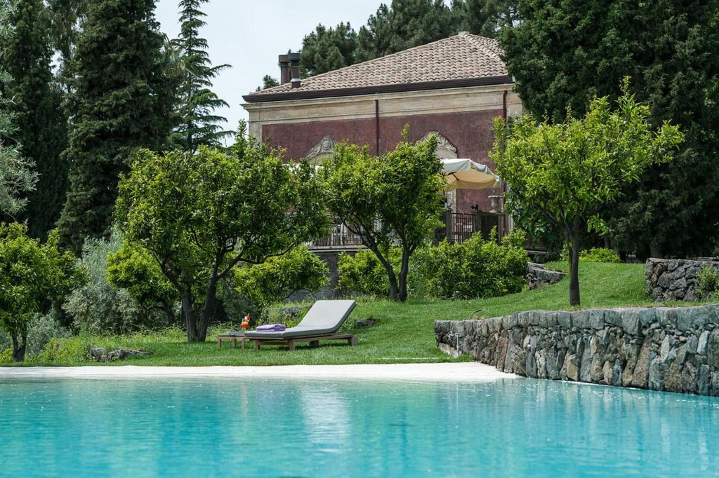 Elegant Italian boutique hotel nestled on Mount Etna's slopes, featuring stone walls, lush gardens and panoramic vineyard views