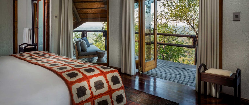 Luxurious lodge suite perched on rocky cliffs with panoramic African savanna views, featuring infinity pool and private terrace