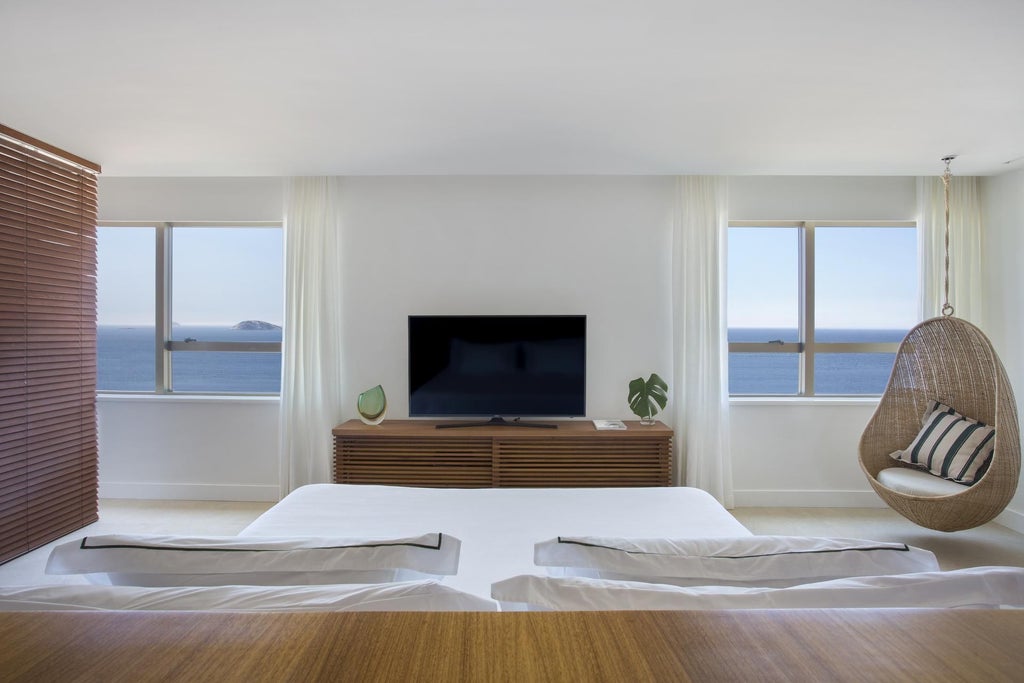 Elegant modern suite at Janeiro Hotel featuring panoramic ocean views, minimalist design, floor-to-ceiling windows, and sophisticated Brazilian coastal aesthetic