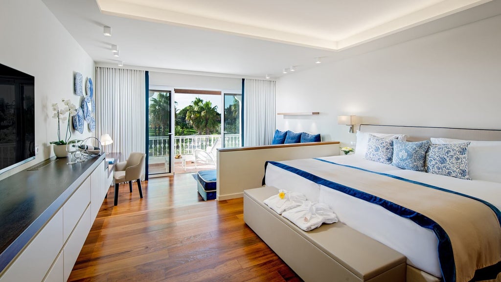 Elegant deluxe garden view room at Vila Vita Parc Resort & Spa, featuring plush white bedding, modern decor, and glimpse of verdant Portuguese landscape