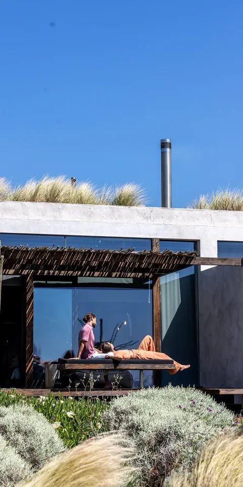 Minimalist luxe tree-house style bedroom with natural wood, panoramic windows overlooking coastal landscape at Areias do Seixo, Portugal.