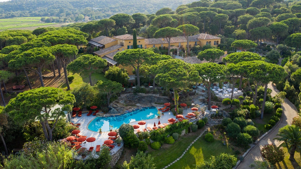 Luxurious Mediterranean villa-style hotel nestled in lush gardens, with elegant white facade, azure swimming pool, and Saint-Tropez coastal charm