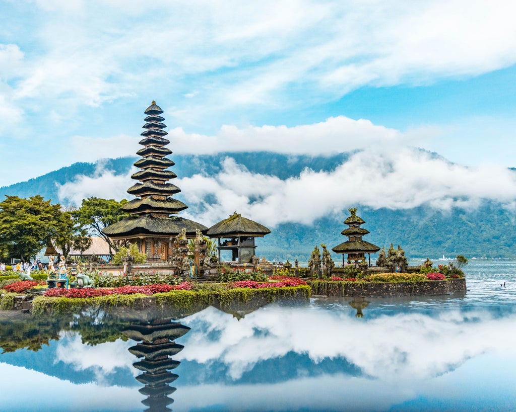 Tranquil infinity pool overlooking lush tropical jungle in Bali, with traditional thatched-roof villas nestled among swaying palm trees