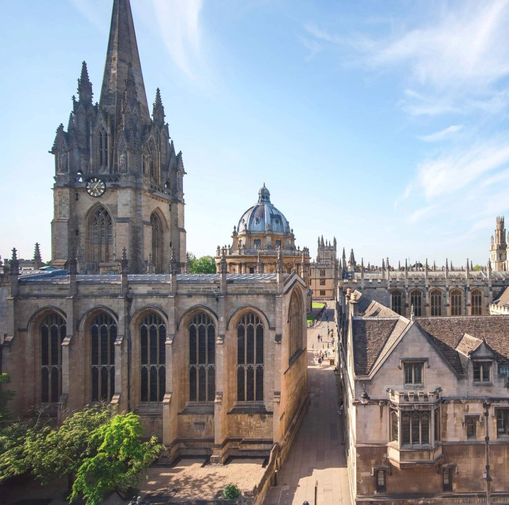 Luxurious heritage hotel room with panoramic windows overlooking historic urban landscape, showcasing elegant period furnishings and refined architectural details.