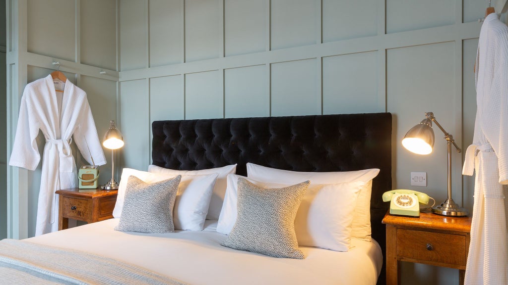 Elegant UK hotel room with modern shower, neutral color palette, plush bedding, and minimalist design featuring soft natural lighting and chic contemporary furnishings.