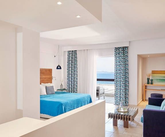 Elegant Deluxe Junior Suite at Eagles Palace hotel, featuring expansive Aegean Sea view, luxurious contemporary design, and pristine white-blue color palette