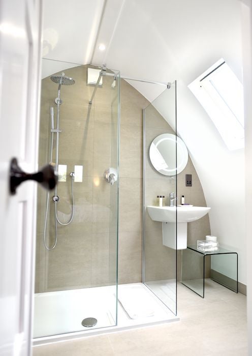 Luxurious rustic hotel room at Tuddenham Mill with exposed wooden beams, crisp white linens, and elegant countryside view through large windows