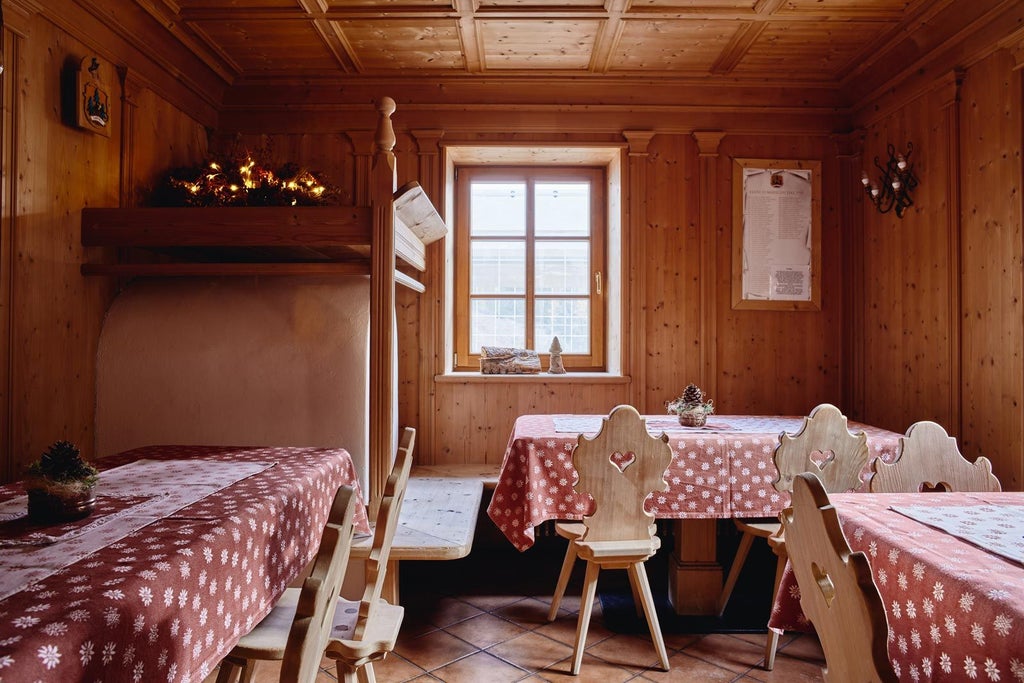 Rustic wooden mountain lodge hotel surrounded by snow-capped Dolomite peaks, featuring traditional alpine architecture and balconies