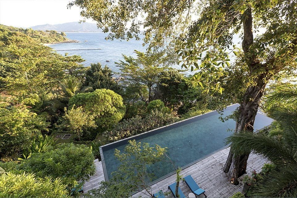 Infinity pool overlooking Andaman Sea at luxury resort, with sun loungers and tropical foliage framing panoramic ocean views