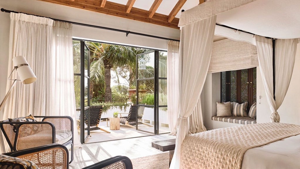 Elegant Mediterranean-style hotel room with white furnishings, cream-colored textiles, and panoramic sea view from private balcony at luxury resort