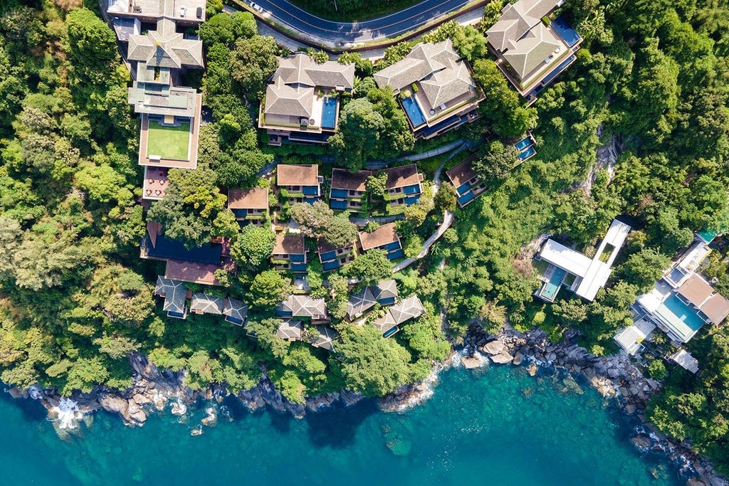 Luxurious infinity pool overlooking lush Thai jungle, with modern sunbeds and private villa terrace surrounded by tropical gardens