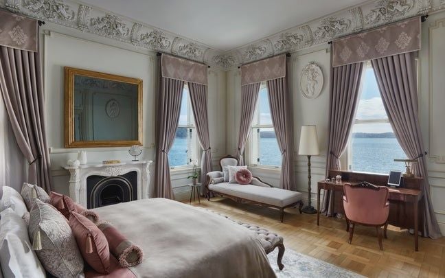 Elegant historic suite with ornate Turkish decor, plush bed, antique furnishings, and large windows overlooking Istanbul's scenic landscape at Six Senses Kocatas Mansions