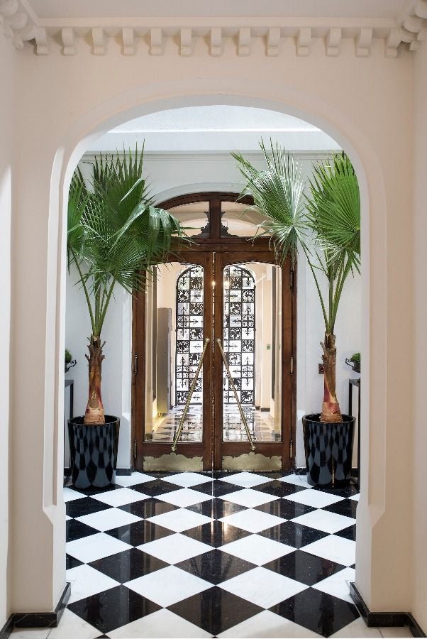 White neoclassical boutique hotel with ornate stonework facade, featuring tall arched windows and black wrought iron balconies in Santiago, Chile