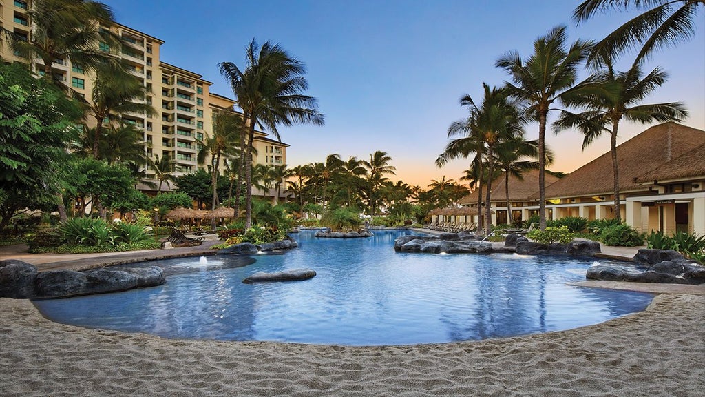 Luxurious beachfront resort with palm trees, turquoise waters, and elegant Hawaiian-style architecture of the tropical Scenset hotel complex