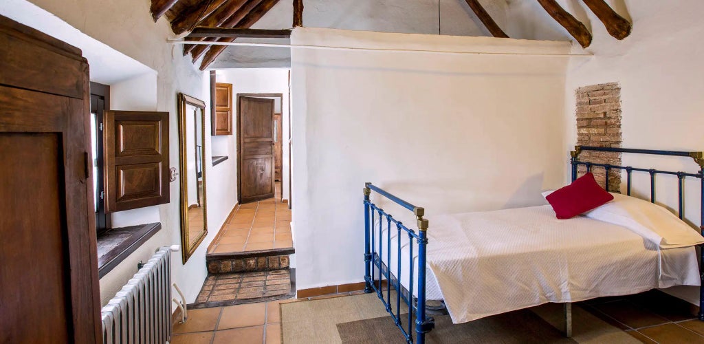 Elegant whitewashed Spanish cottage with rustic wooden furniture, terracotta tiles, and warm natural light filtering through arched windows at Cortijo del Marqués