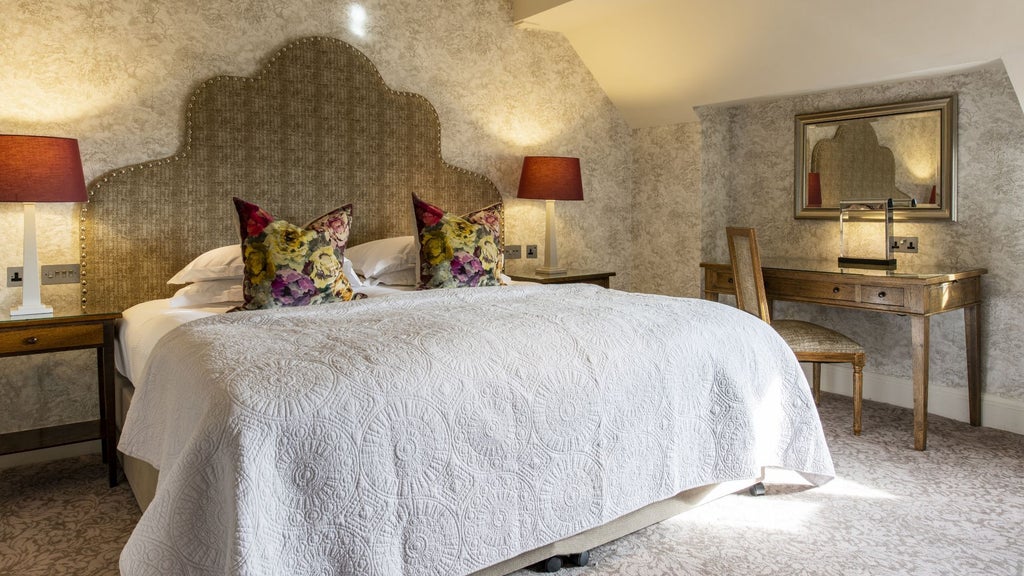 Elegant stone-walled castle room with plush four-poster bed, ornate period furnishings, and large windows overlooking scenic countryside at Scenset Hotel in the United Kingdom.