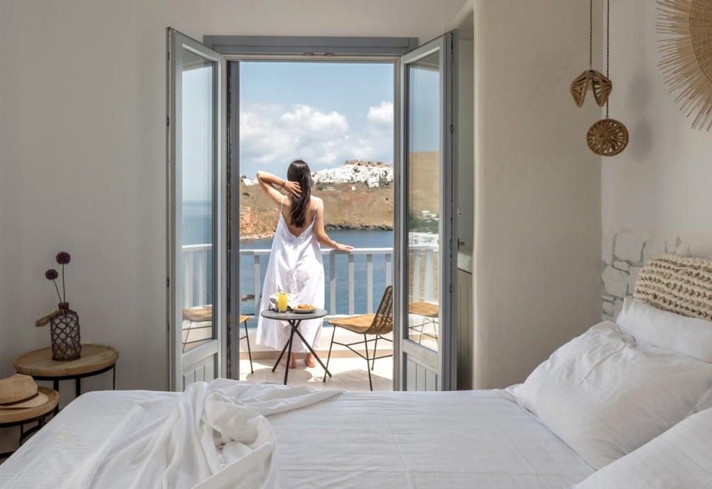 Elegant honeymoon suite with white minimalist decor, panoramic Aegean Sea view, luxurious king bed, and clean Mediterranean design in Greece