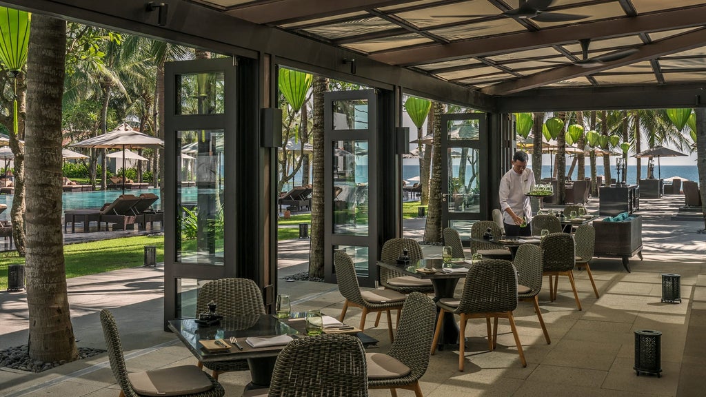 Luxurious beachfront villa with infinity pool at Four Seasons Nam Hai, set against a backdrop of palm trees and the East Vietnam Sea