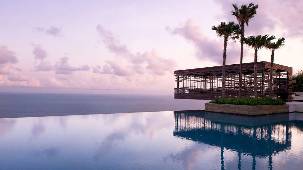 Luxurious ocean-front villa perched on Uluwatu cliffs, featuring an infinity pool that blends with the Bali sea at sunset