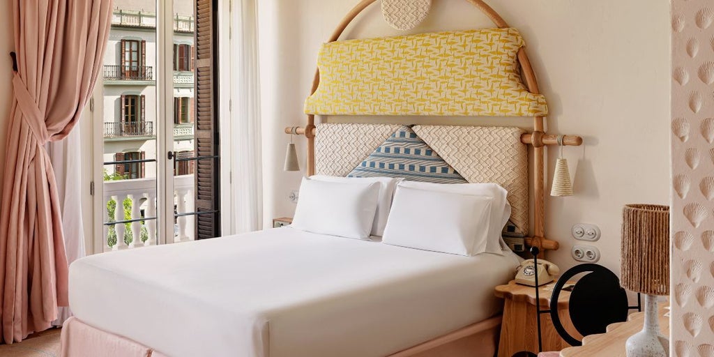 Minimalist white bedroom with elegant wooden furniture, soft lighting, and panoramic view of Eivissa coastline in luxurious Scenset hotel room