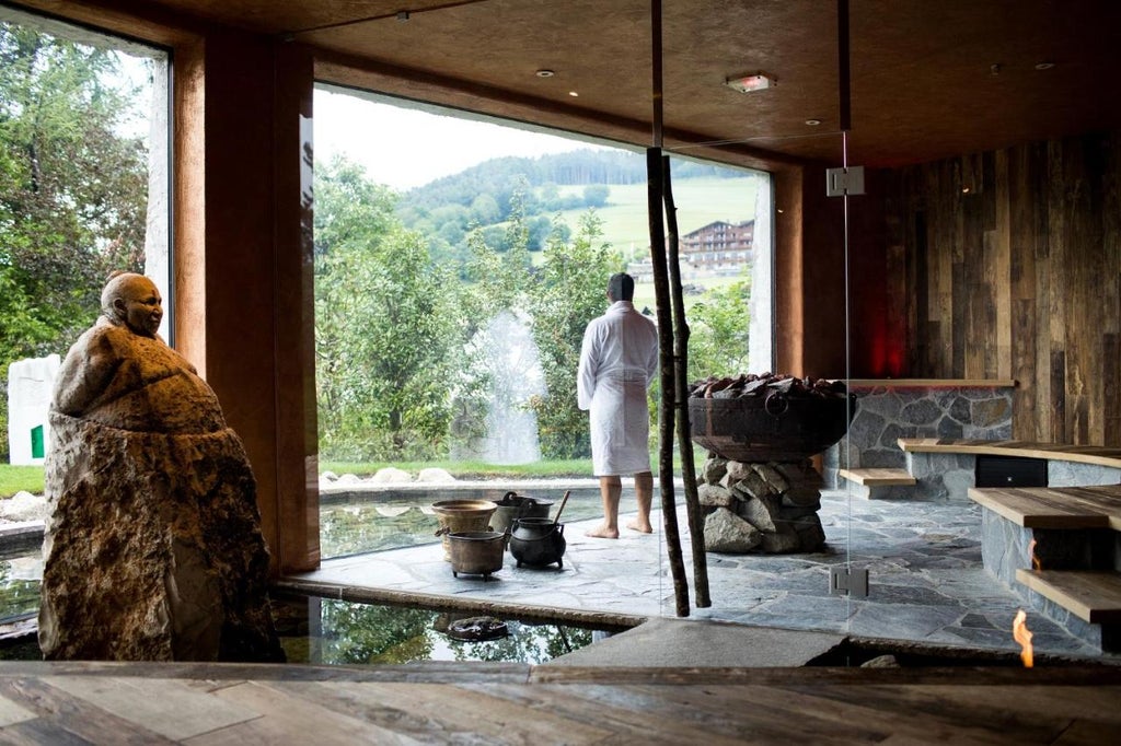 Elegant stone hotel with rustic tower overlooking snow-capped Dolomite mountains, featuring traditional South Tyrolean architecture