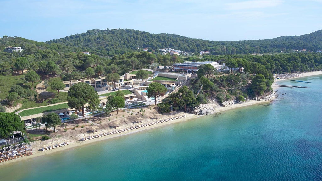 Luxurious beachfront resort with modern white architecture, azure Aegean waters, and private infinity pool overlooking scenic Skiathos coastline