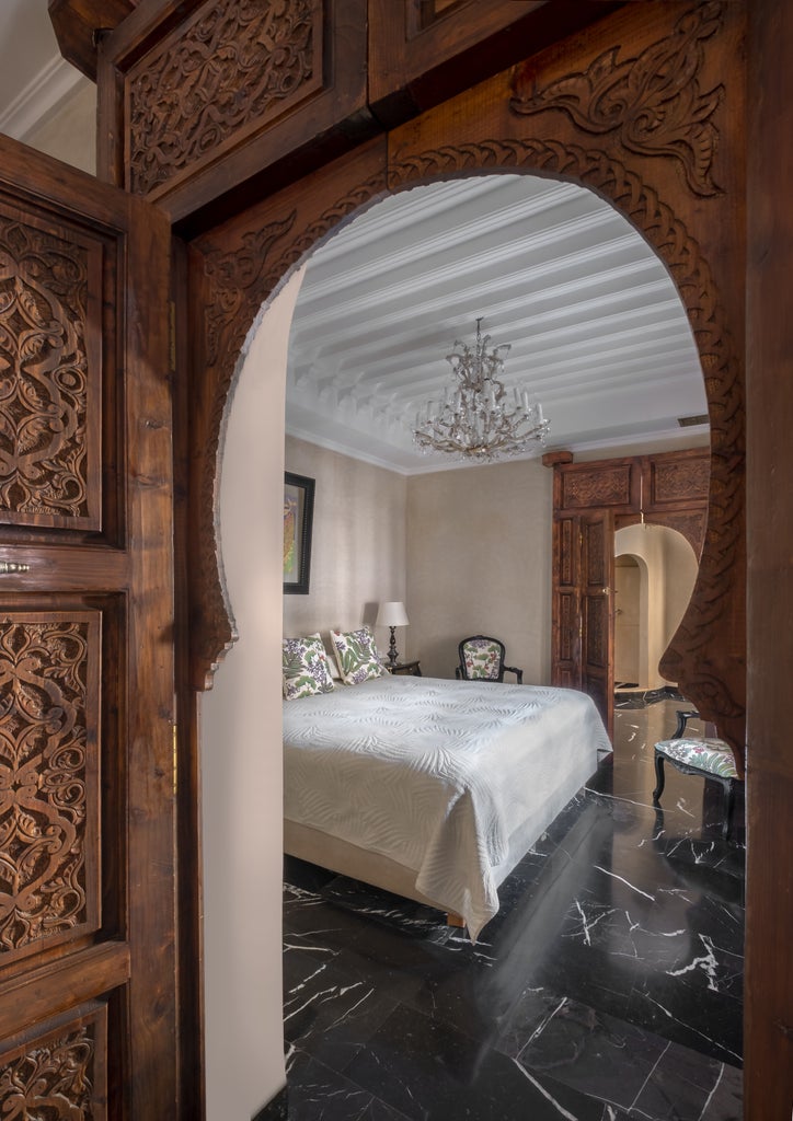 Traditional Moroccan riad featuring ornate archways, luxurious mosaic tilework, and tropical gardens around a serene courtyard pool