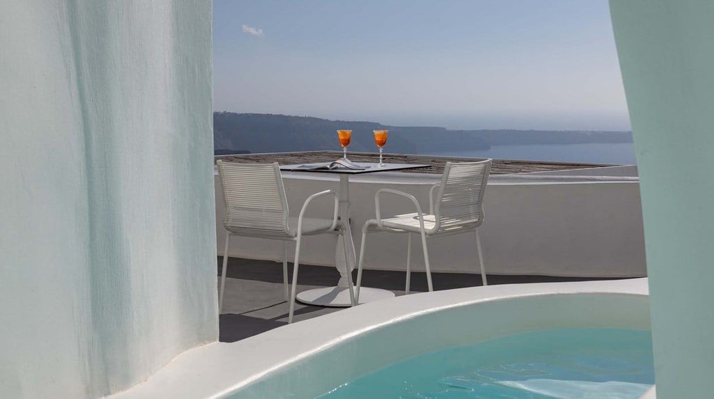 Luxurious white-washed Santorini suite with panoramic Aegean Sea view, private jetted tub, and minimalist elegant design highlighting Greek island architecture