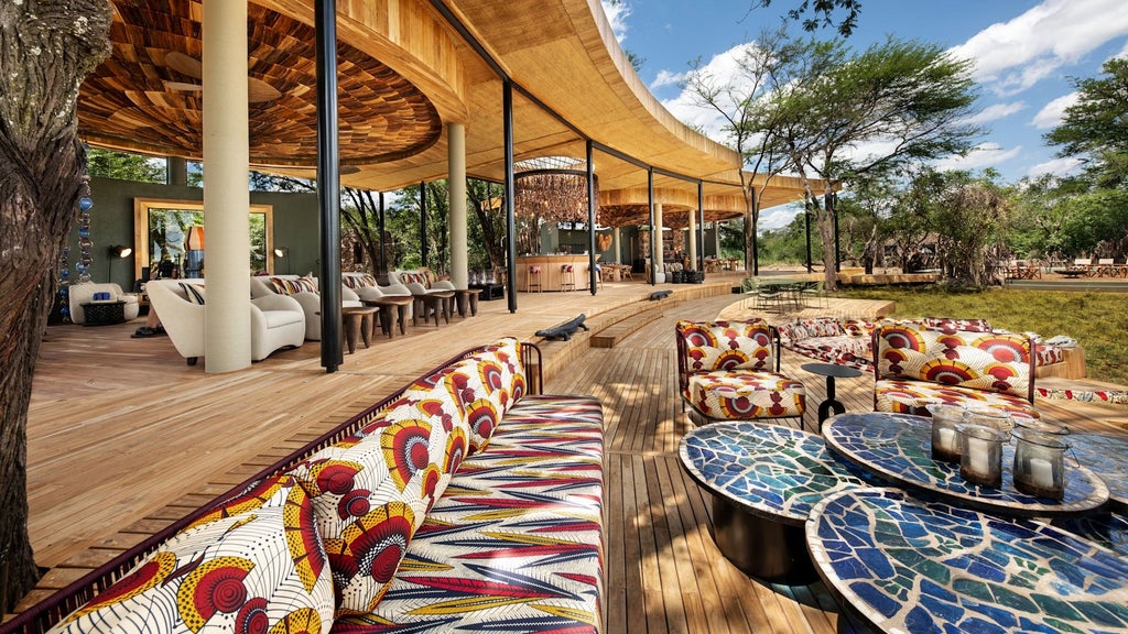 Luxurious safari lodge overlooking Serengeti plains, with infinity pool, thatched roofs, and floor-to-ceiling glass walls bathed in sunset