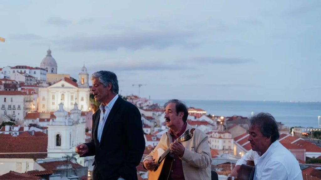 Luxurious boutique hotel terrace overlooking Lisbon's historic Alfama district, with traditional red-tiled roofs and stunning city panorama at sunset