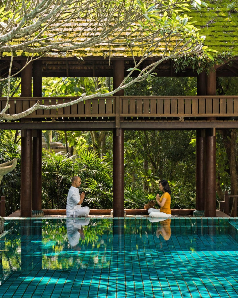 Luxurious Thai villa pavilion surrounded by lush tropical gardens, infinity pool and mist-covered mountains in northern Thailand